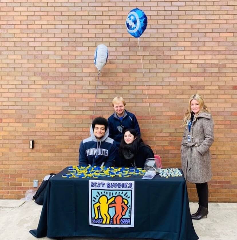 A group of students and a professor at a tabling event for Best Buddies. 